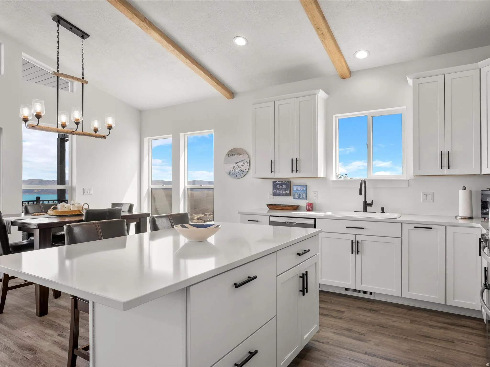 Kitchen with white cabinetry, a kitchen breakfast bar, beam ceiling, dark wood-style flooring, and plenty of natural light