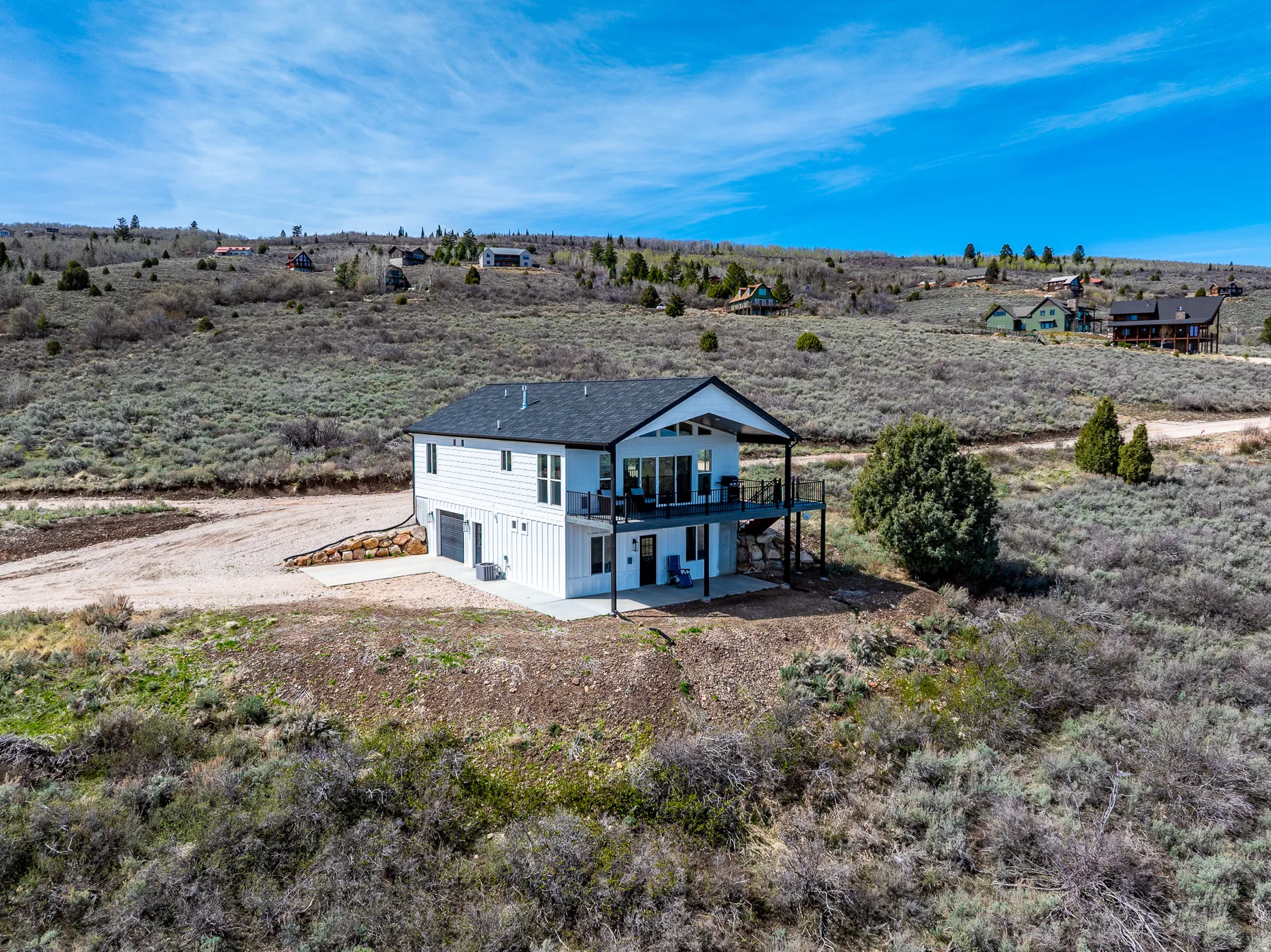 Back of property featuring a patio, a garage, a balcony, driveway, and a view of countryside