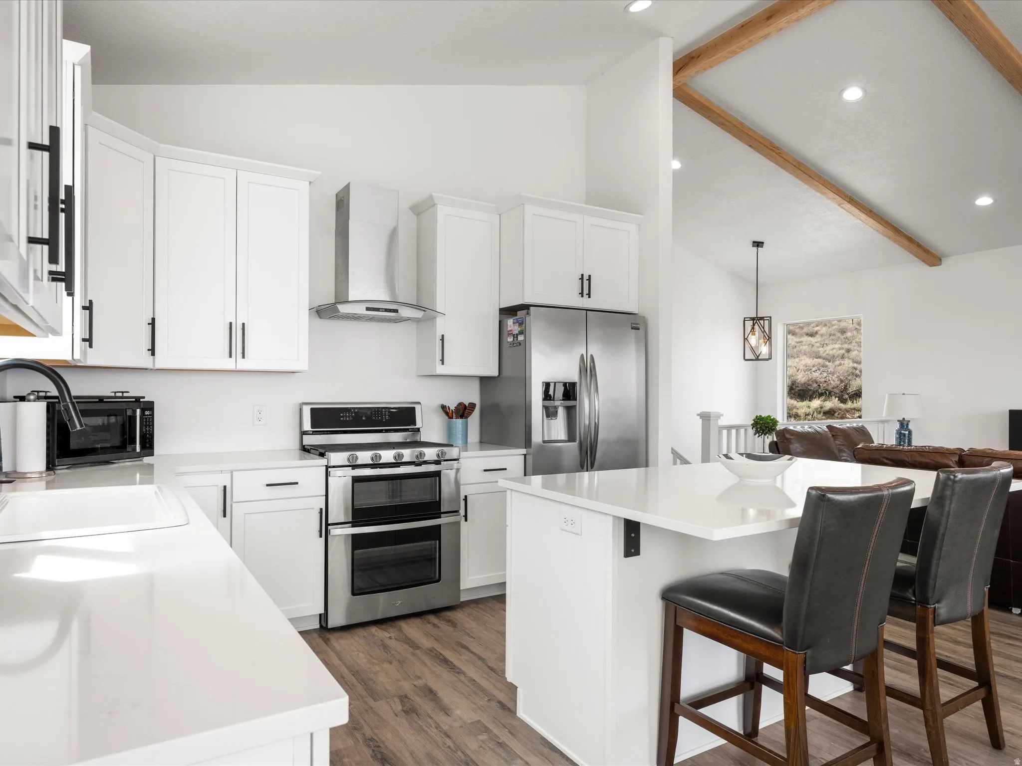 Kitchen with white cabinets, stainless steel appliances, a center island, dark wood finished floors, and a kitchen breakfast bar