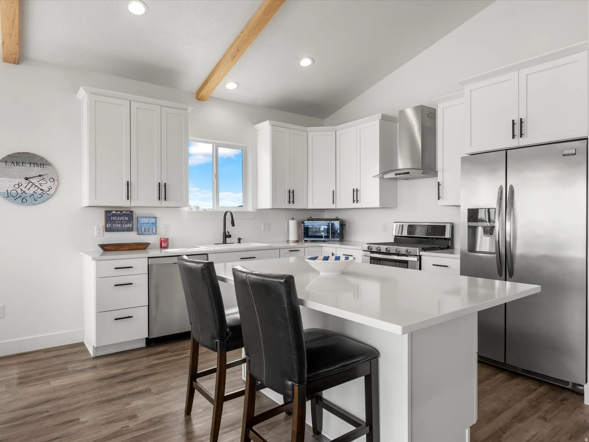 Kitchen with stainless steel appliances, white cabinets, a kitchen bar, a center island, and recessed lighting