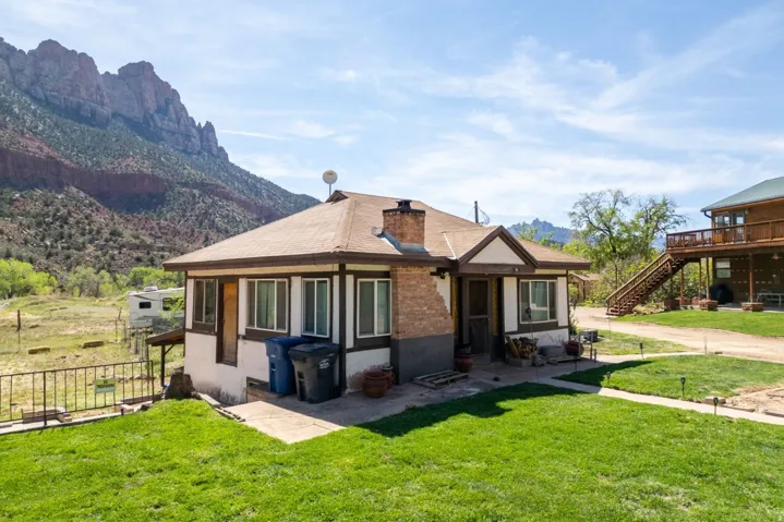 View of front of house with a front yard, a chimney, a mountain view, and stucco siding