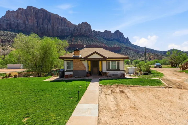 Bungalow-style house featuring a mountain view, a front lawn, a chimney, and an outdoor structure