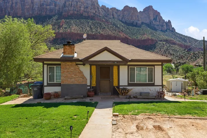 View of front of house with a front lawn, a mountain view, stucco siding, and a storage unit