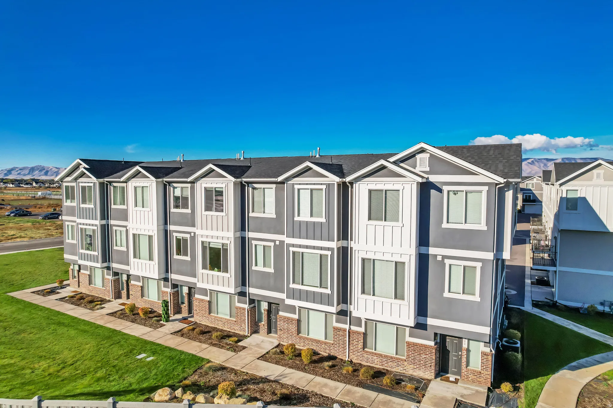View of front of property featuring a front yard, brick siding, a residential view, and board and batten siding