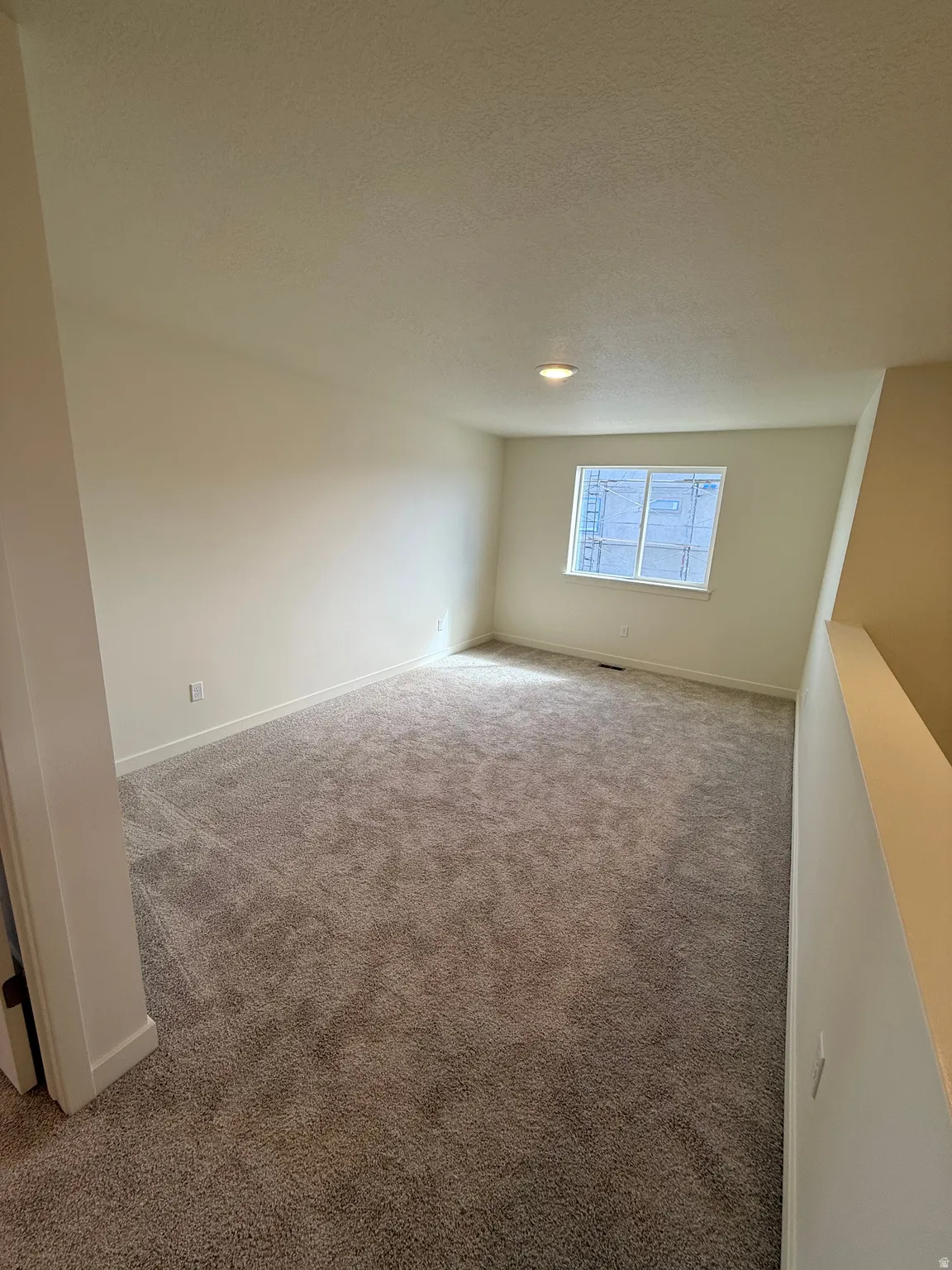 Carpeted room with recessed lighting and a single window