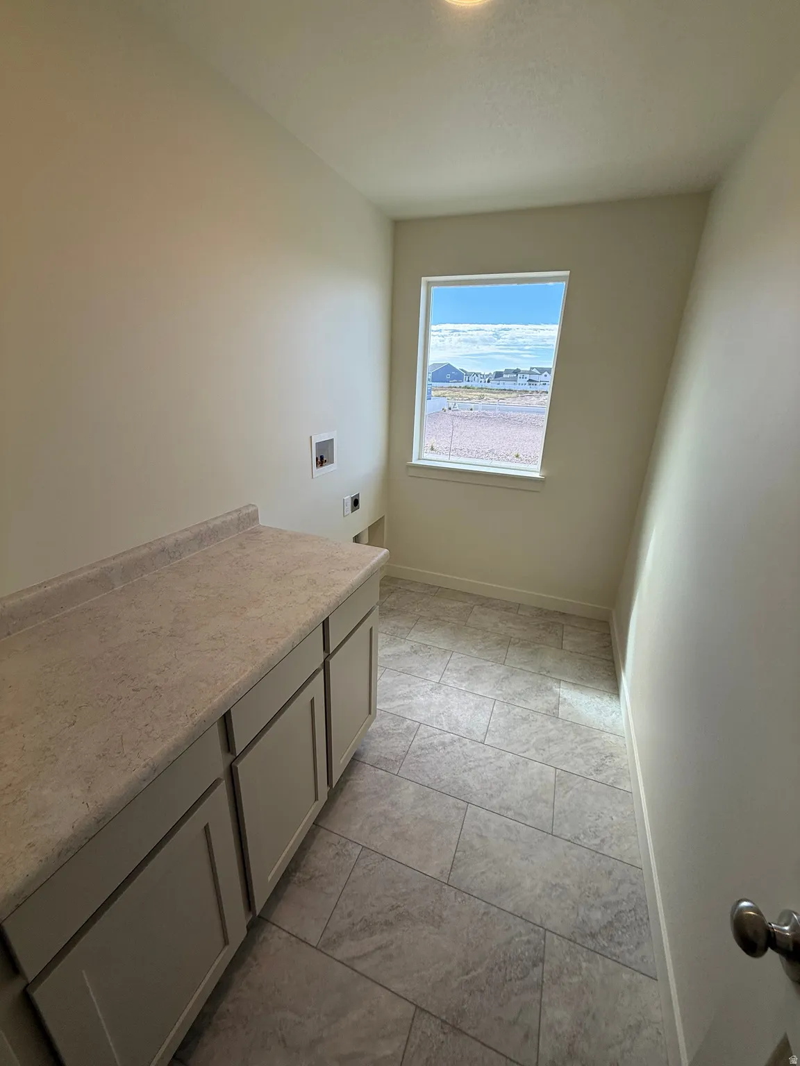 Functional utility room featuring a built-in counter with cabinetry, a single window, and tiled flooring