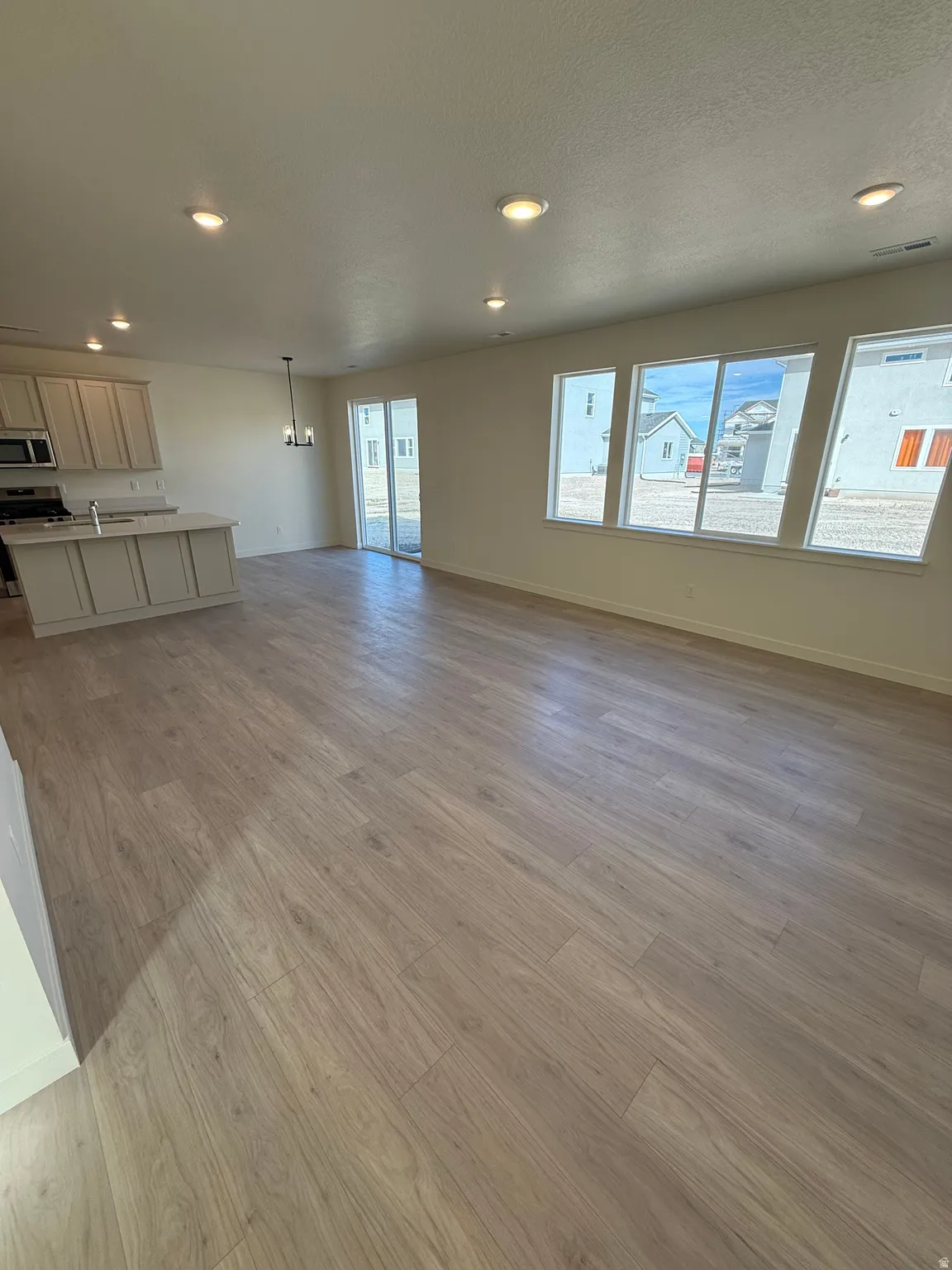 Open-concept living area with wood-finish flooring, recessed lighting, and multiple large windows
