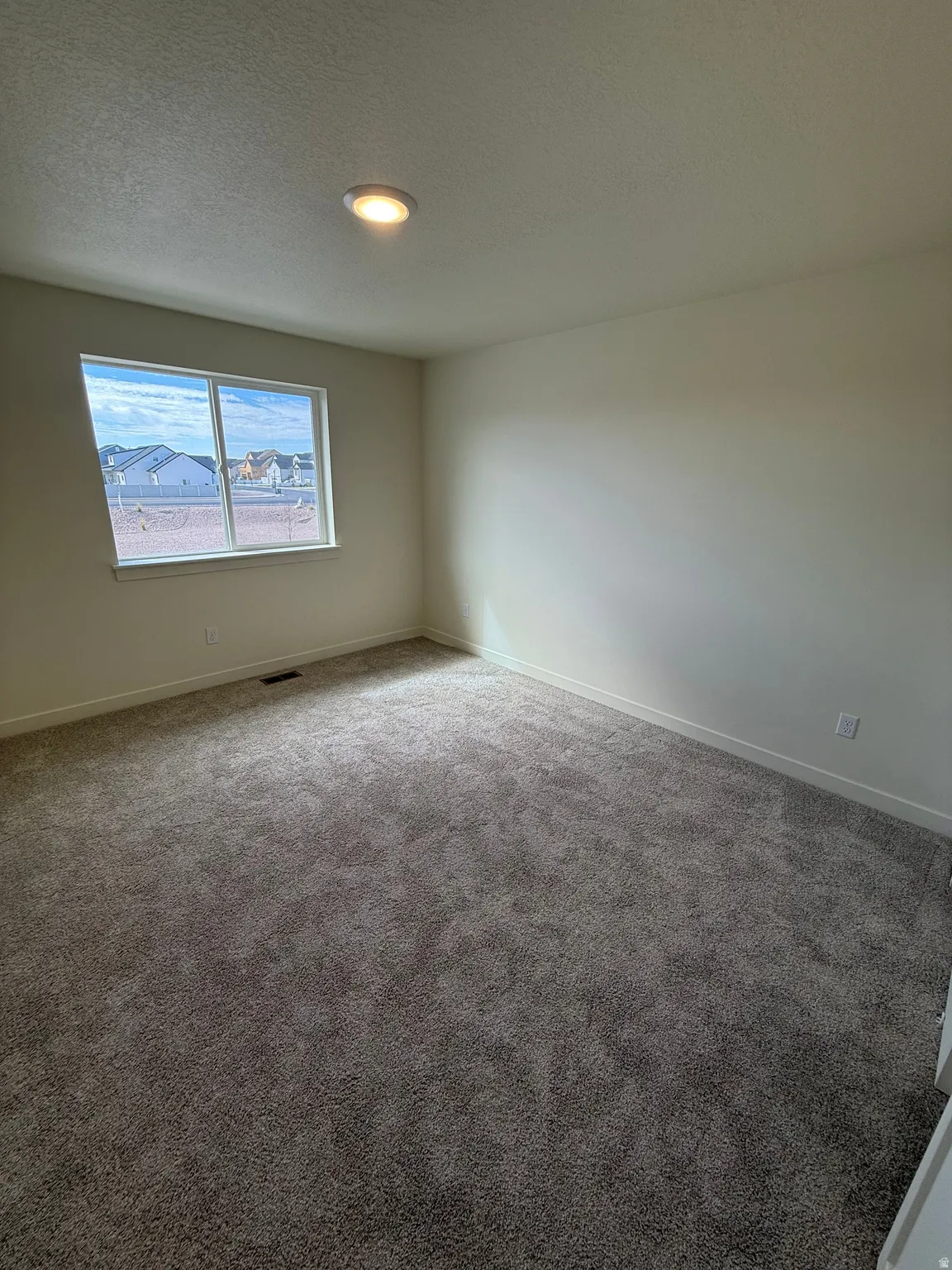 Neutral tone walls, recessed lighting, and grey textured carpet