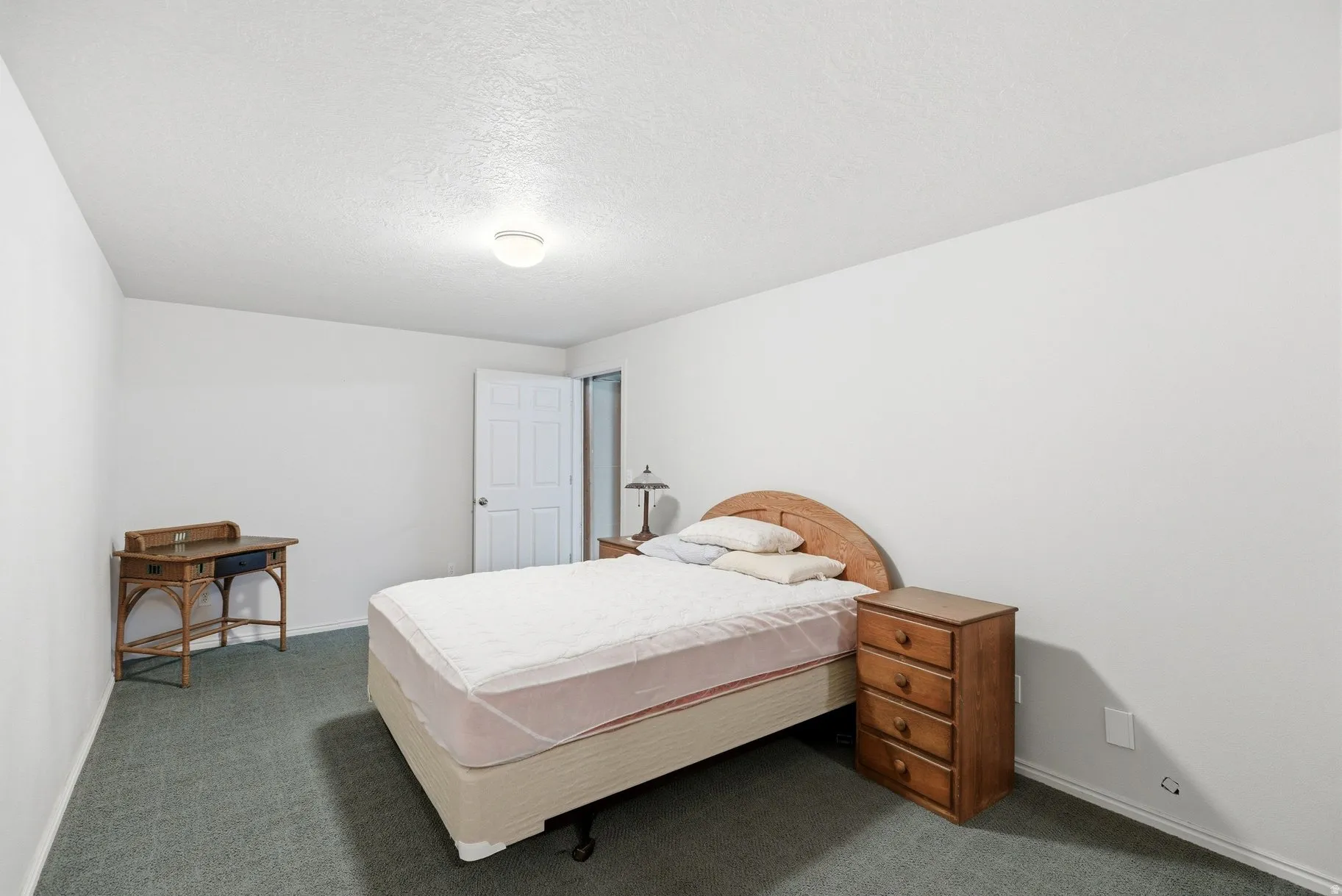 Bedroom featuring dark colored carpet and a textured ceiling