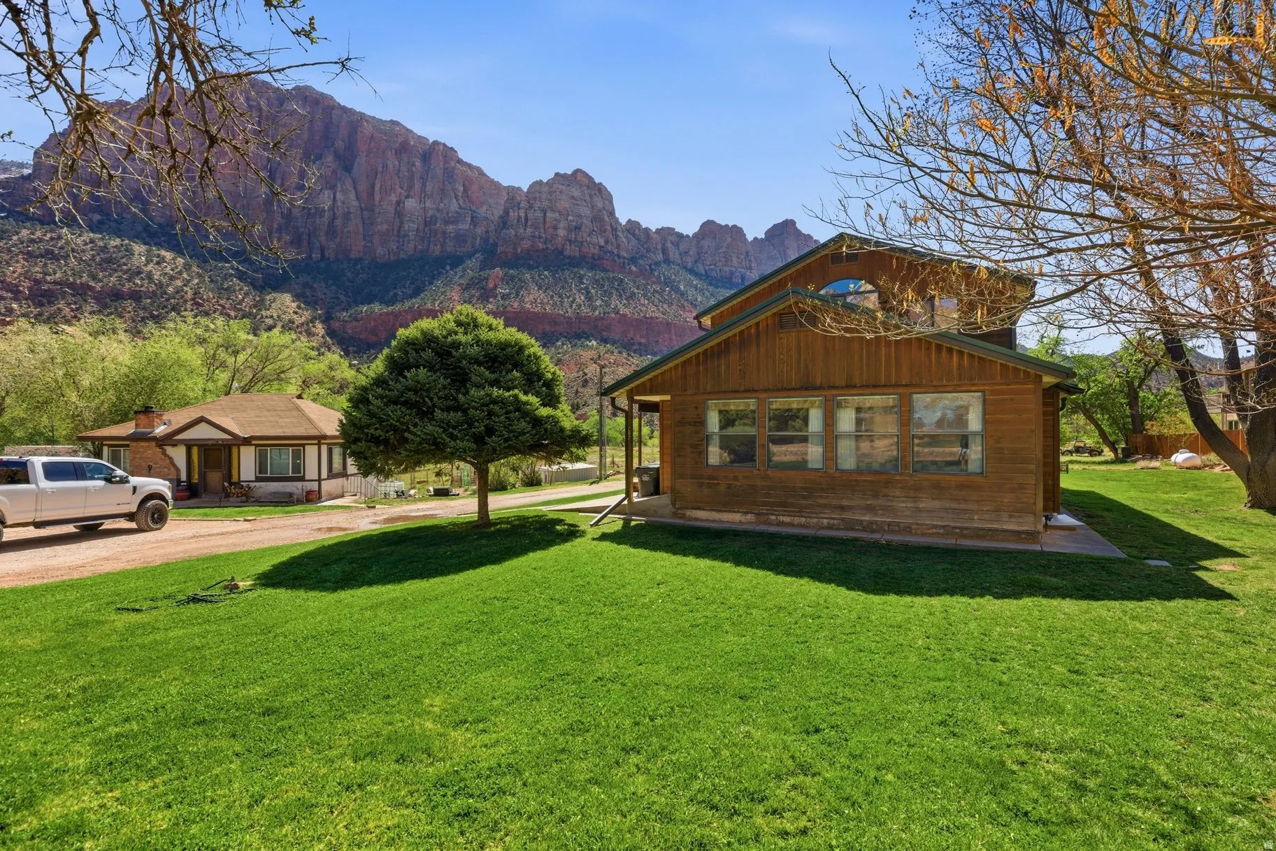 View of property exterior with a mountain view, a lawn, and dirt driveway