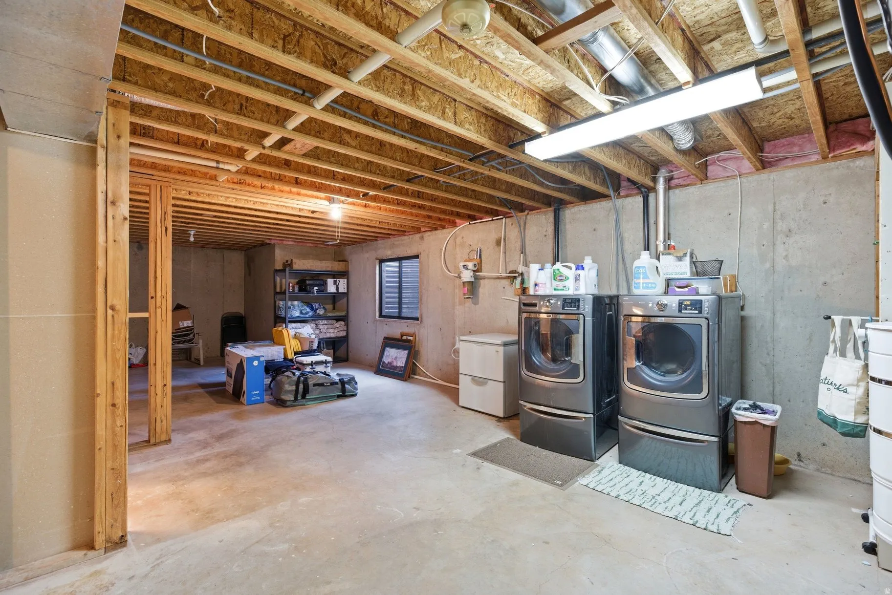 Unfinished below grade area featuring washing machine and clothes dryer