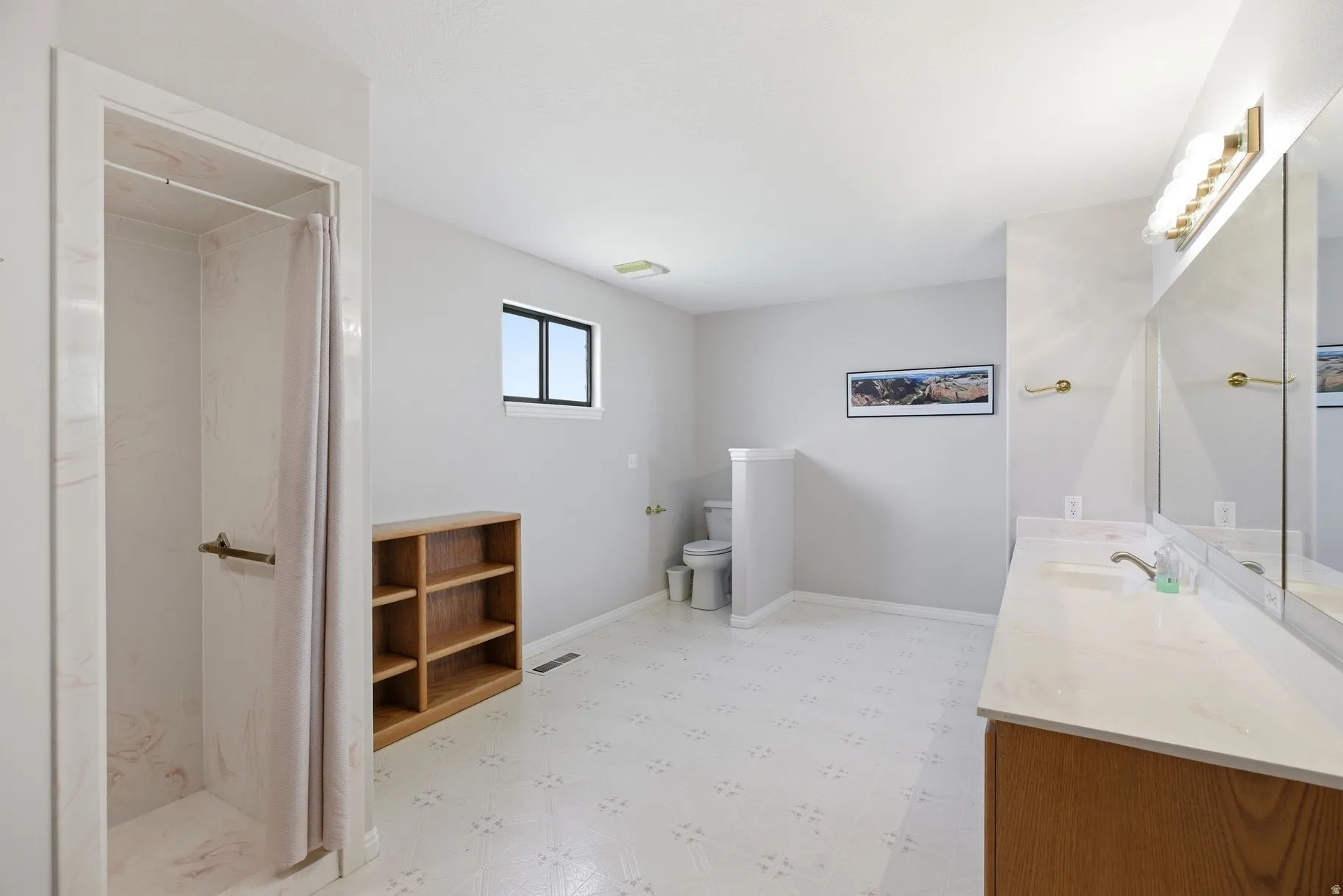Full bathroom featuring light floors, double vanity, and a stall shower
