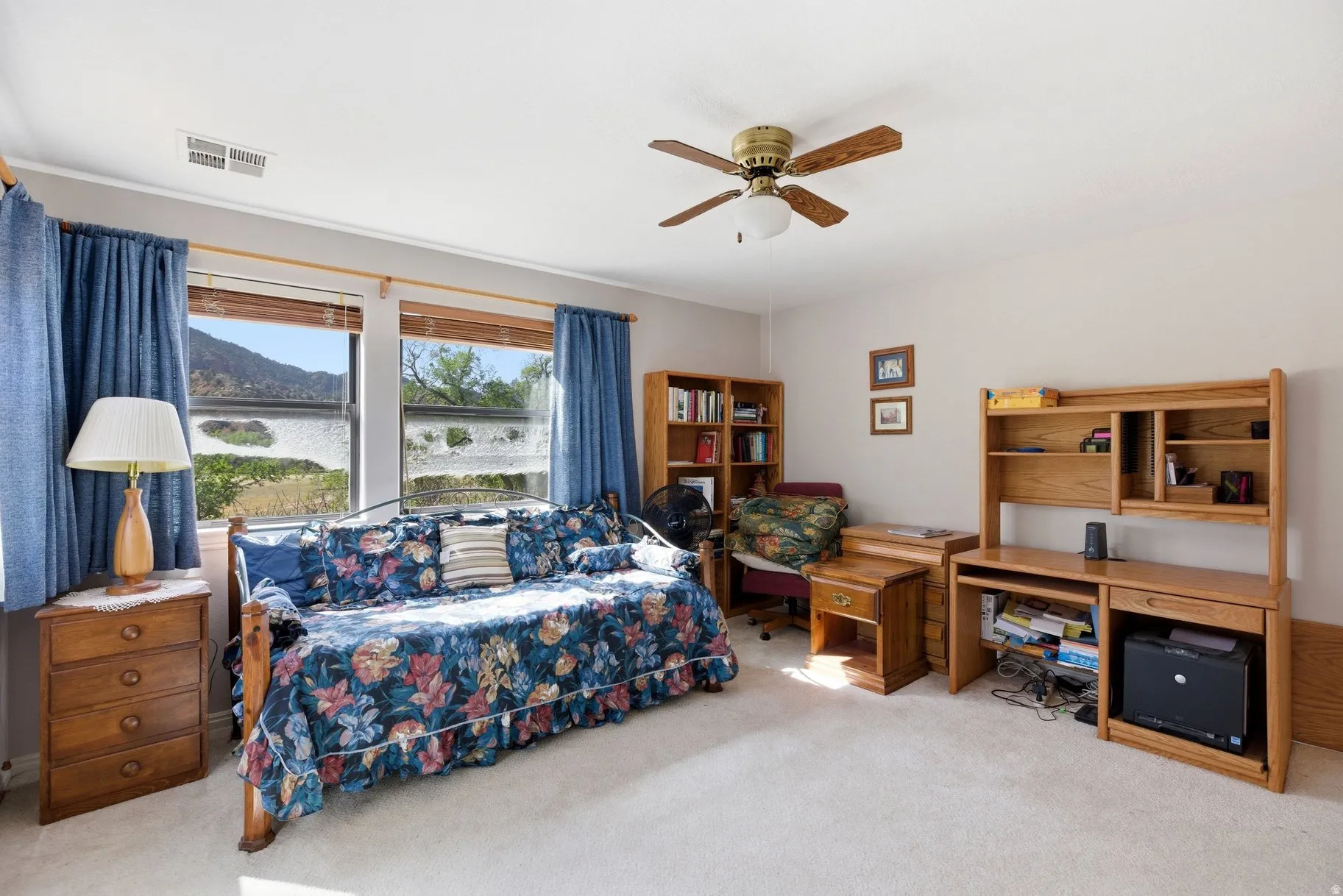 Bedroom featuring light colored carpet, ceiling fan, and an office area