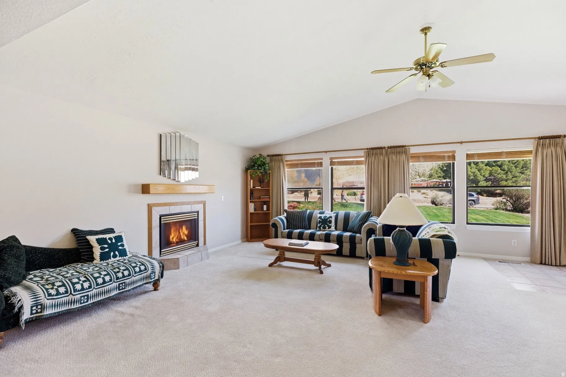 Living area featuring light colored carpet, ceiling fan, and a tile fireplace