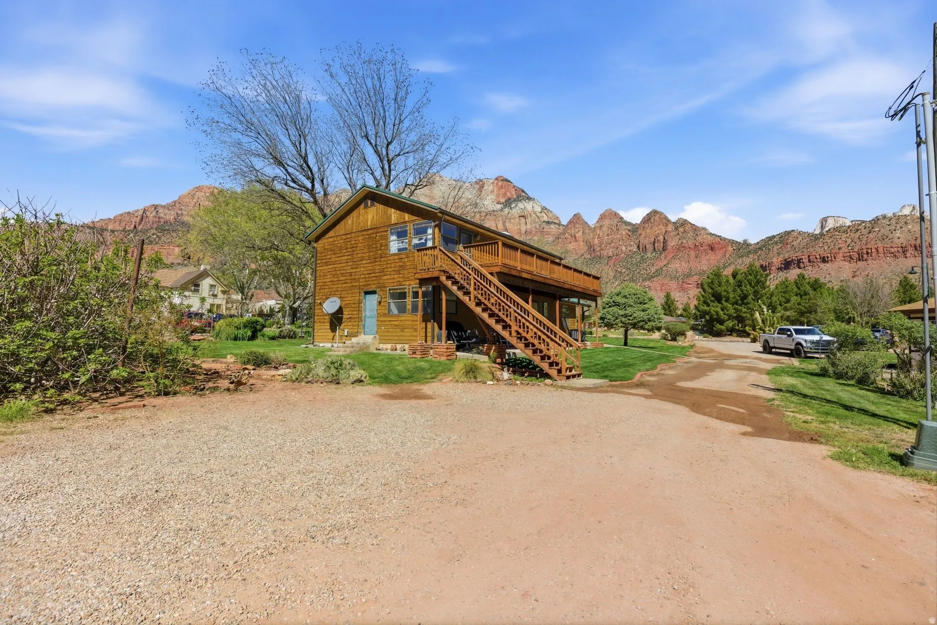 View of front of home featuring a front yard, a deck with mountain view, driveway, and a patio area