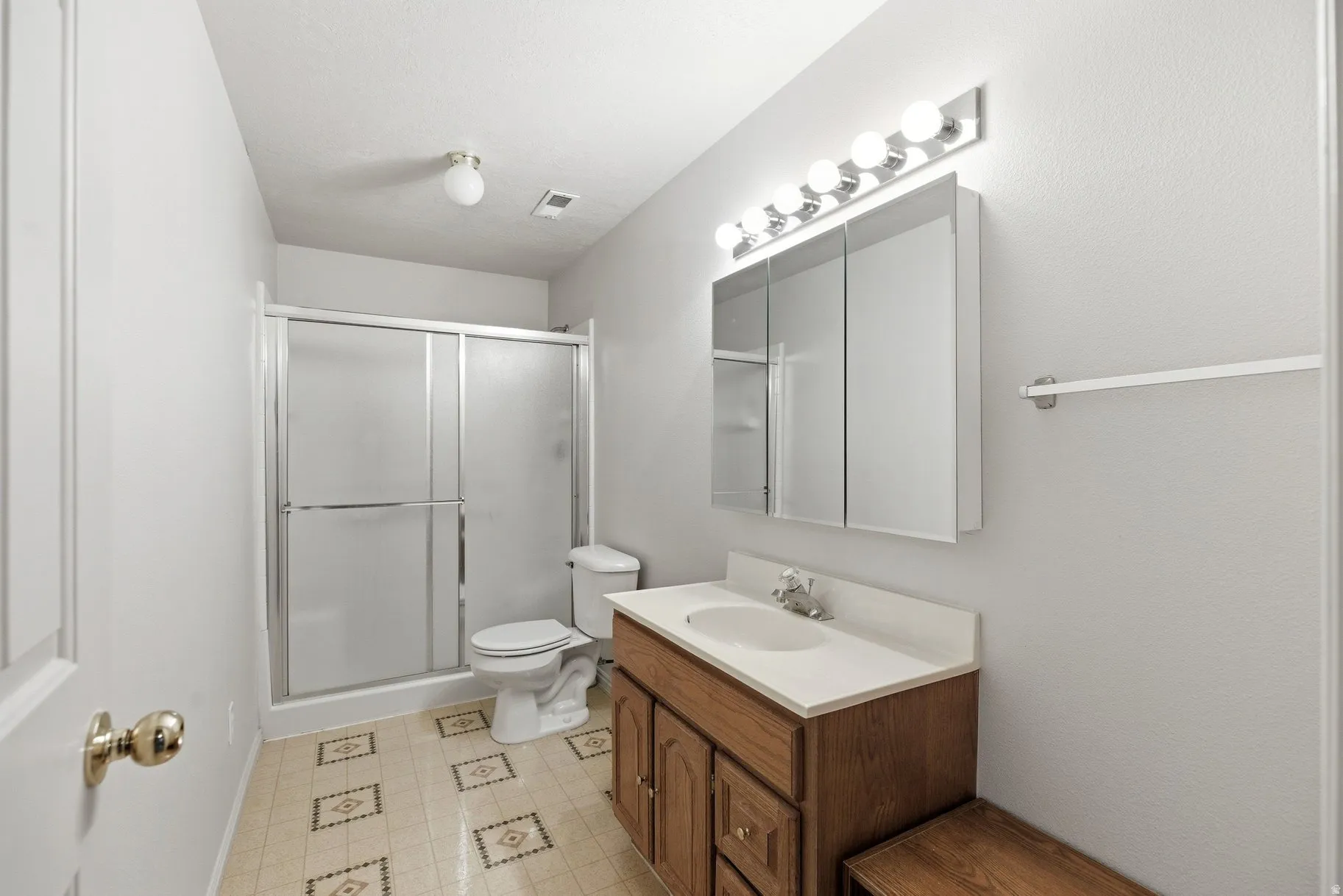 Full bath with a shower stall, vanity, and light floors
