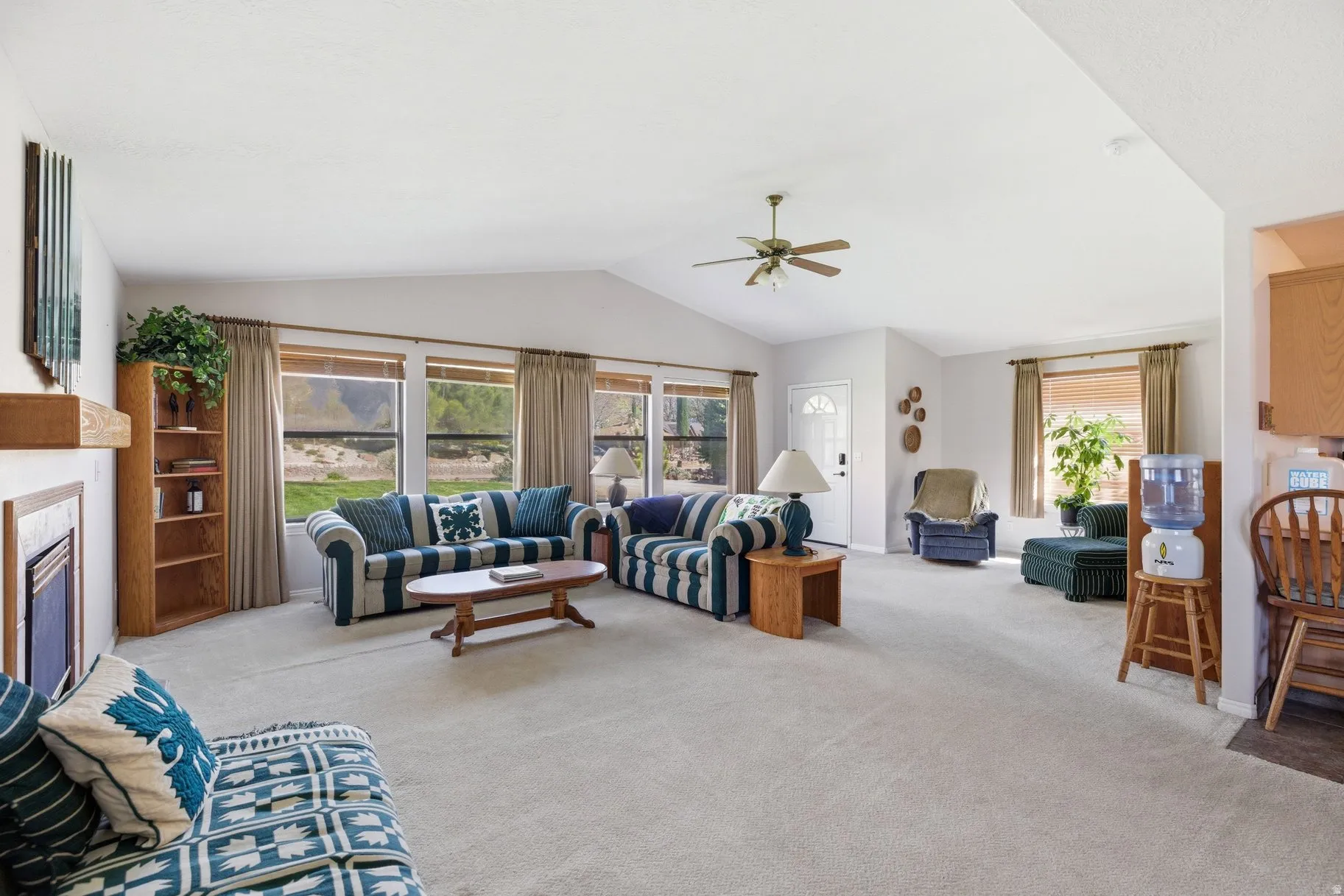 Living area with light carpet, a ceiling fan, and a fireplace