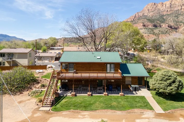 Rear view of property with a mountain view, a patio area, a metal roof, a yard, and a balcony