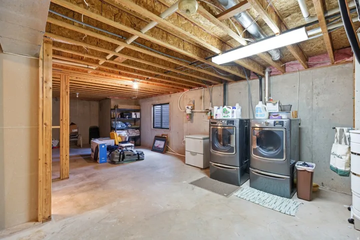 Unfinished below grade area featuring washing machine and clothes dryer