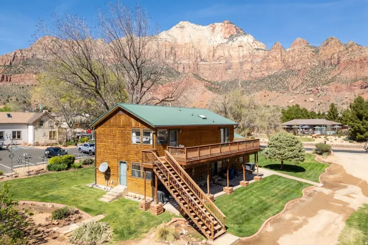 Rear view of house featuring a lawn, a deck with mountain view, and a metal roof