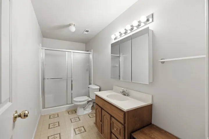 Full bath with a shower stall, vanity, and light floors