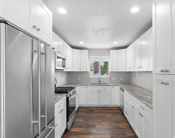 Kitchen featuring stainless steel appliances, white cabinetry, dark wood-style floors, recessed lighting, and light stone countertops