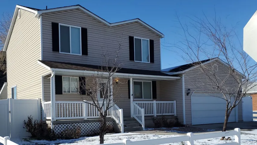 View of front of home with an attached garage, covered porch, and driveway