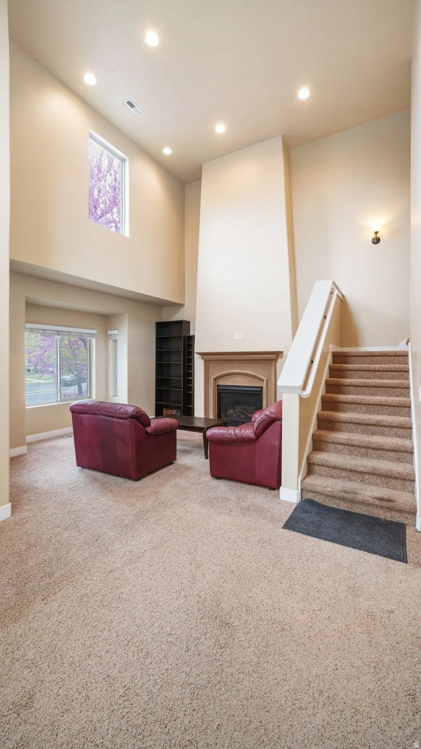 Living area featuring a high ceiling, carpet flooring, a fireplace, and recessed lighting