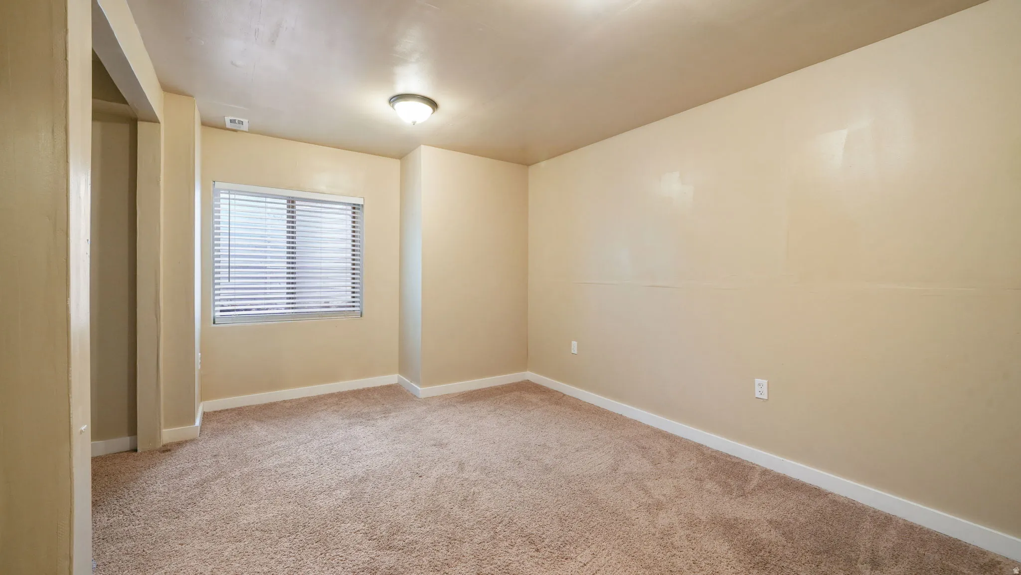 Unfurnished bedroom with light colored carpet and baseboards