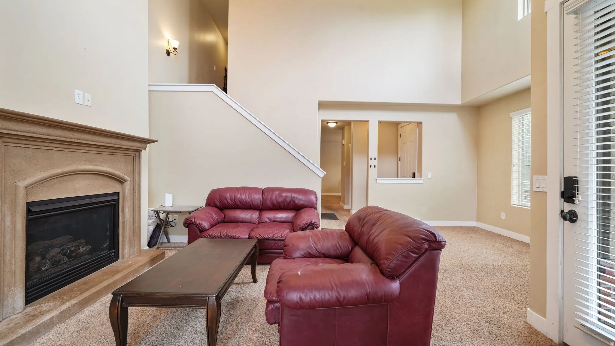 Living area with carpet floors, a glass covered fireplace, and a high ceiling