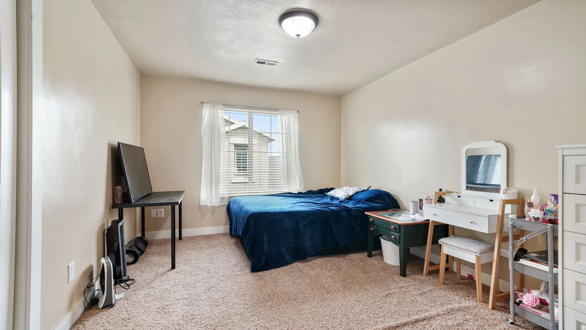 Bedroom featuring light colored carpet and a textured ceiling