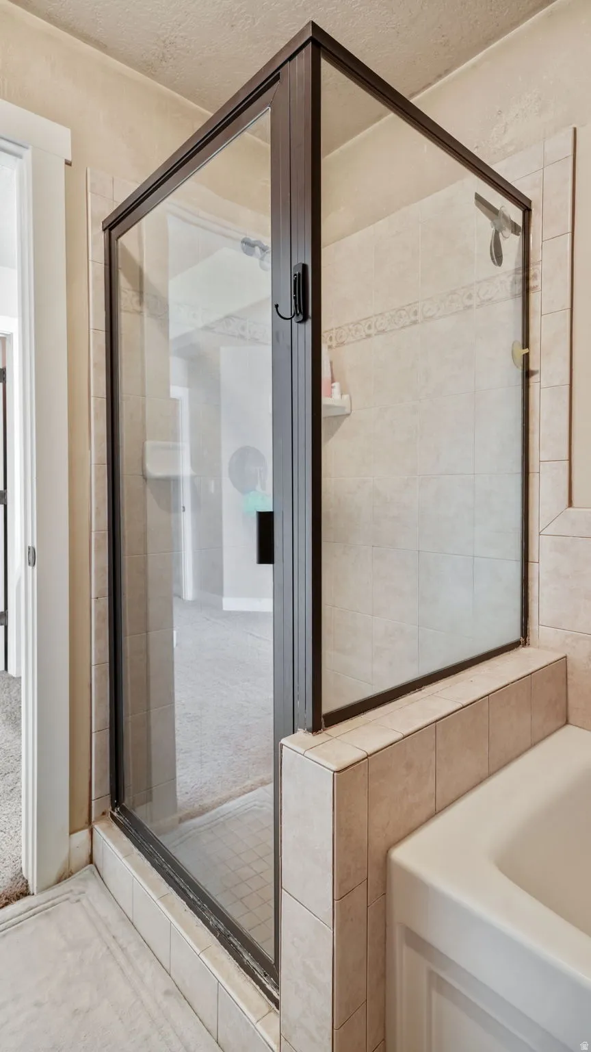 Full bathroom with a shower stall, a textured ceiling, and a garden tub
