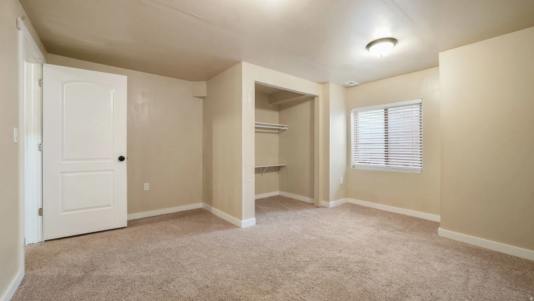 Unfurnished bedroom with light carpet and a closet
