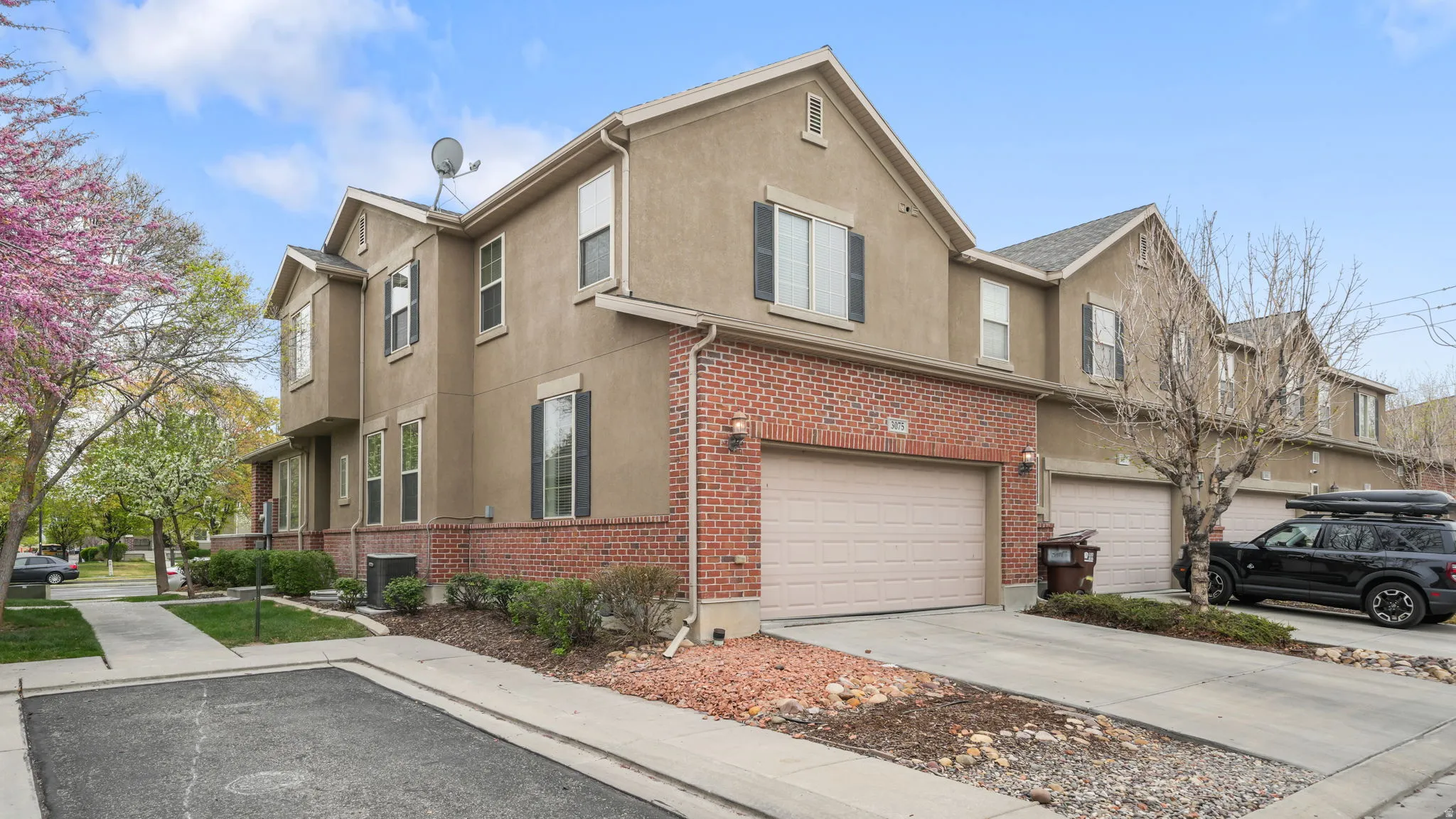 View of side of property with stucco siding, brick siding, an attached garage, and concrete driveway