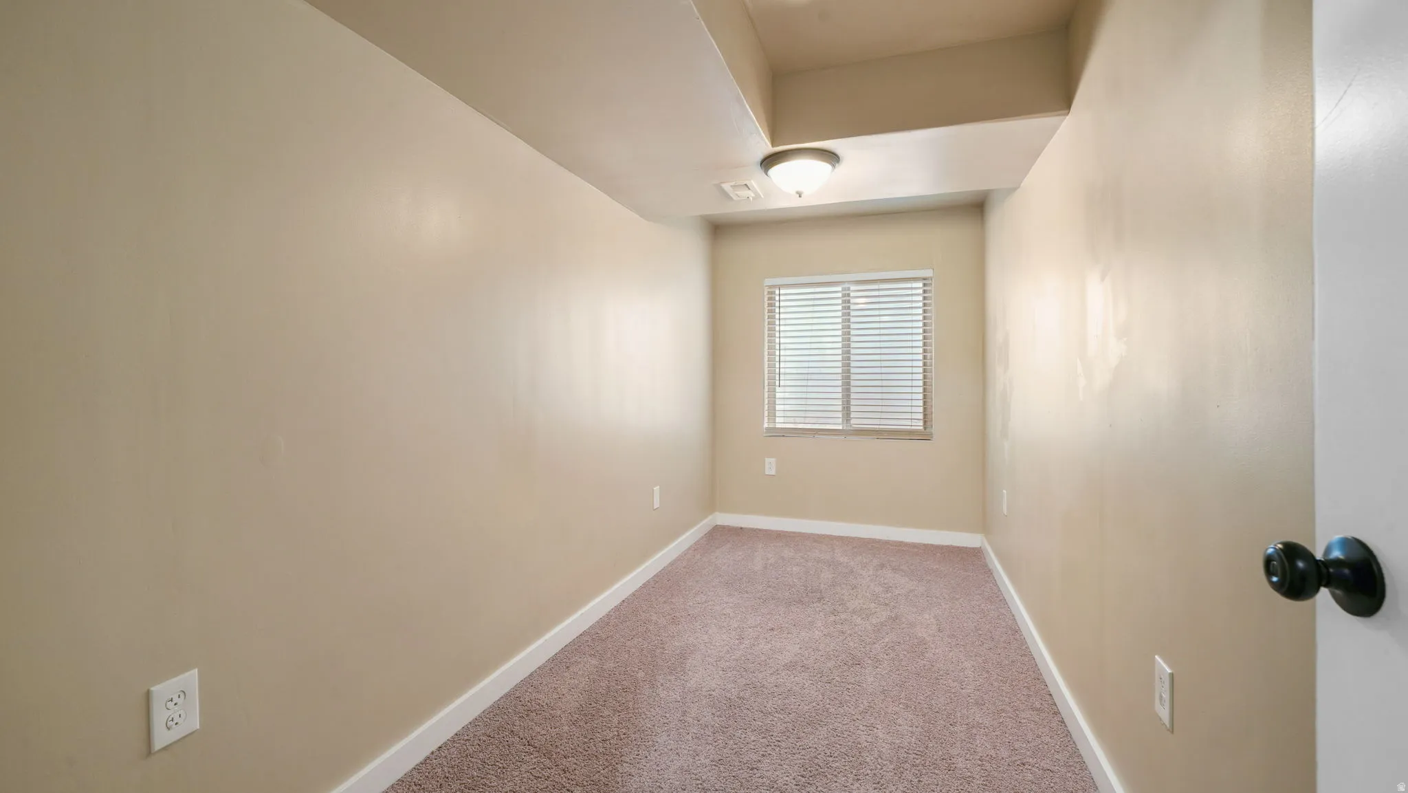 Empty room with light colored carpet and baseboards