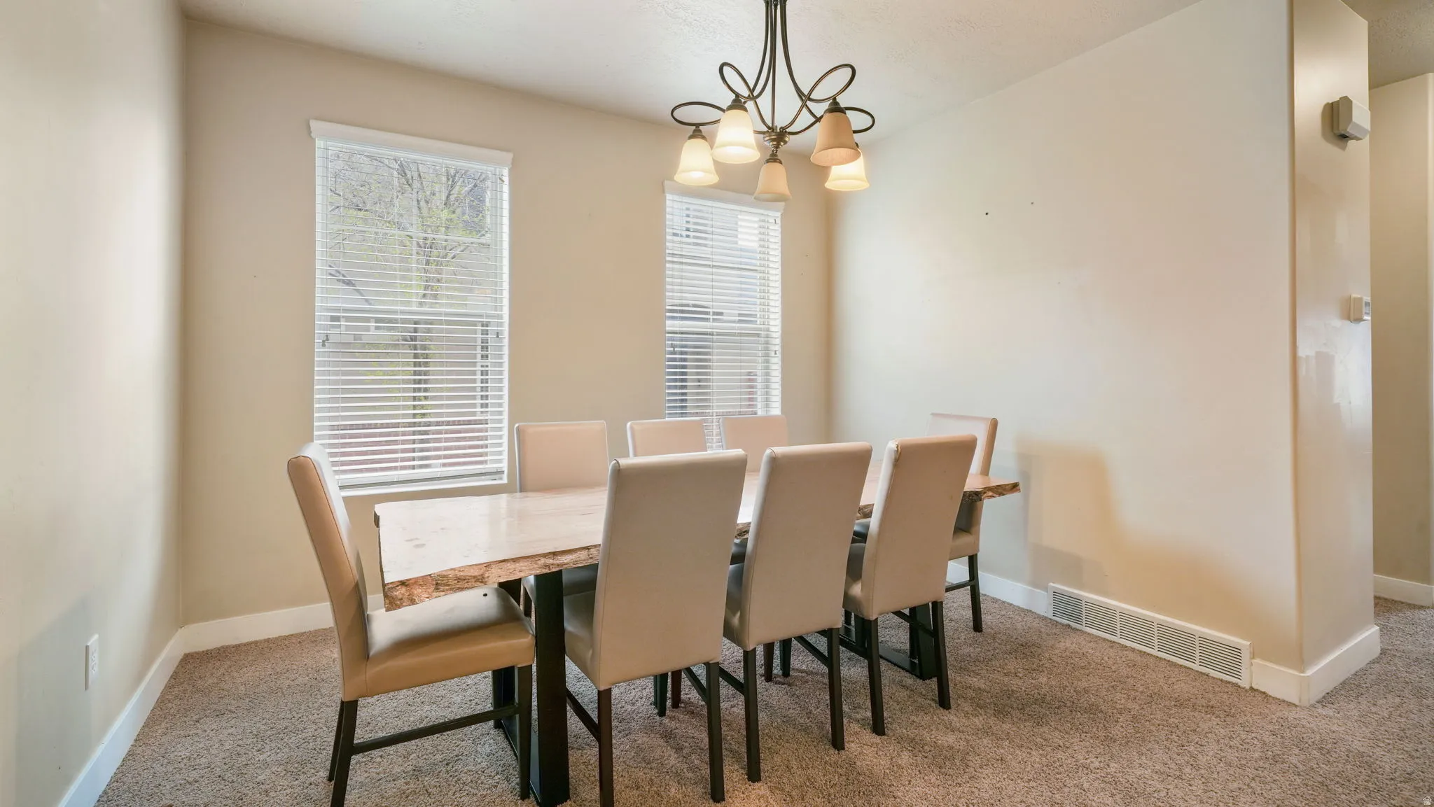 Dining area featuring suspended lighting and light colored carpet