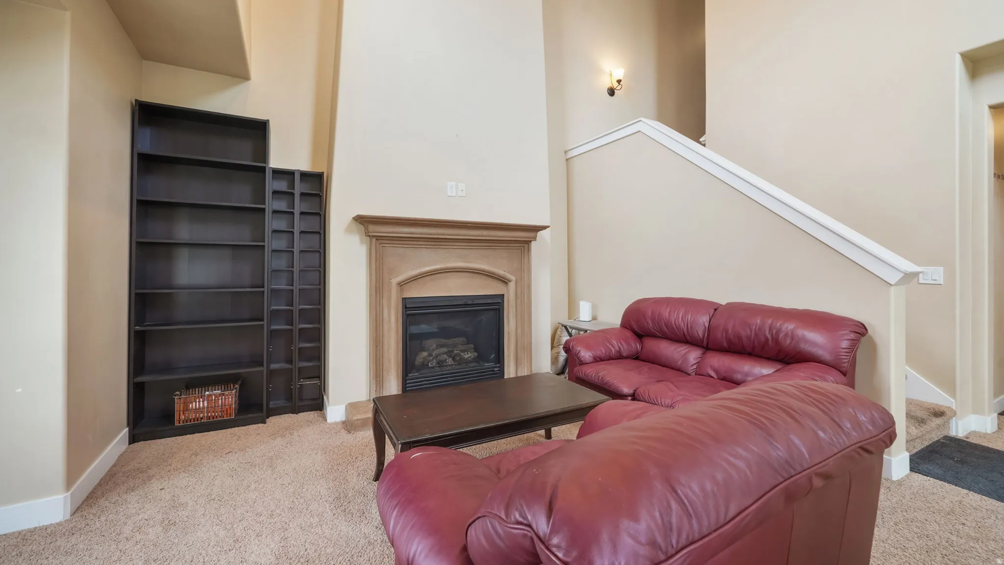 Carpeted living room featuring stairway and a glass covered fireplace