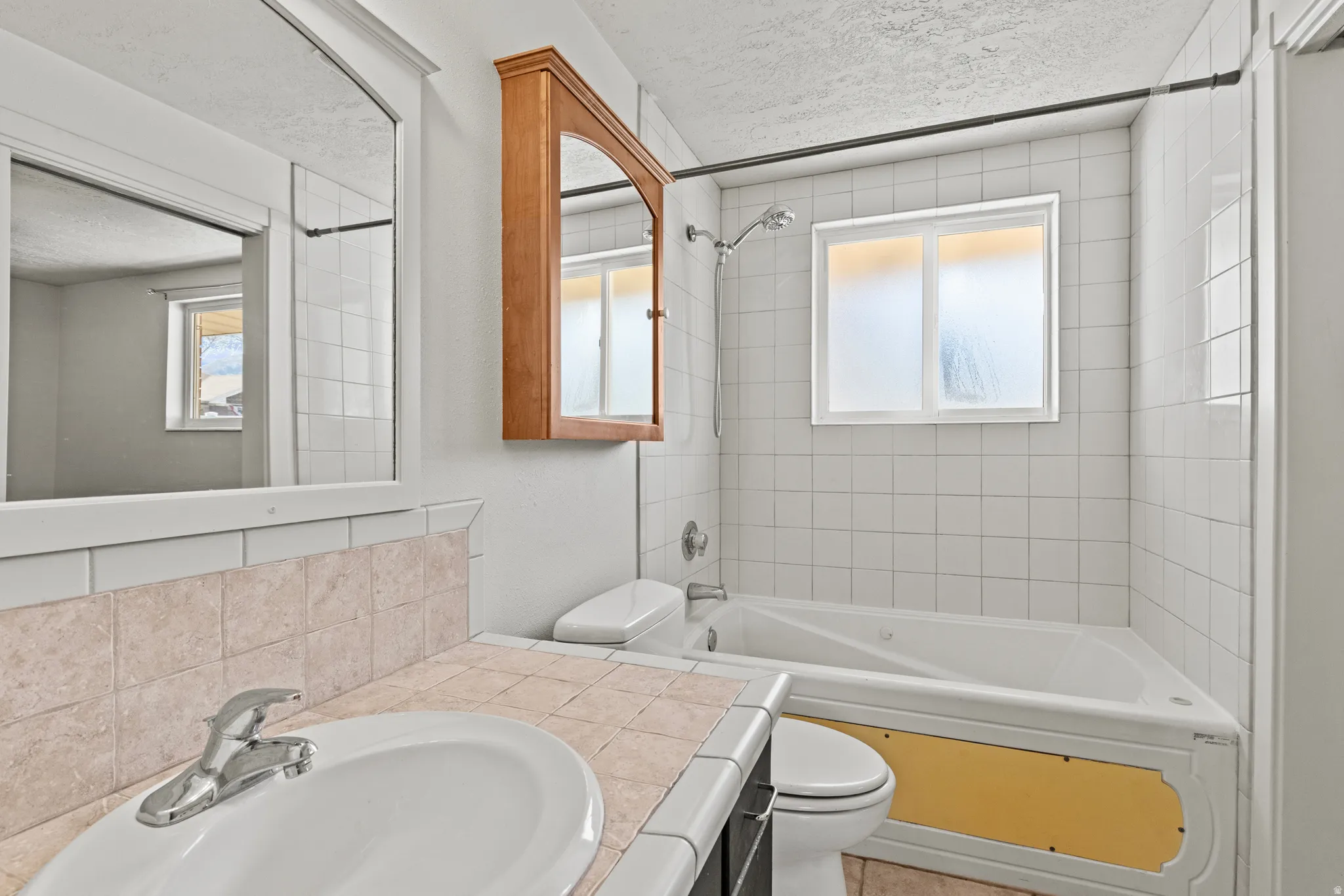 #813 Full bath featuring vanity, Jetted bathtub / shower combination, a textured ceiling, and plenty of natural light