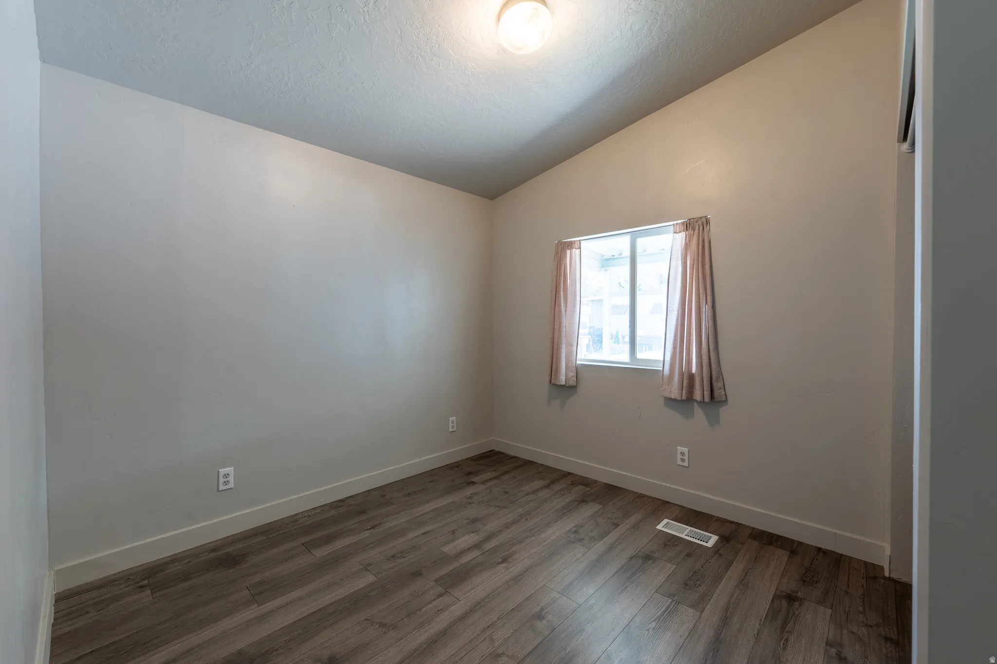 Unfurnished room featuring dark wood-type flooring and baseboards