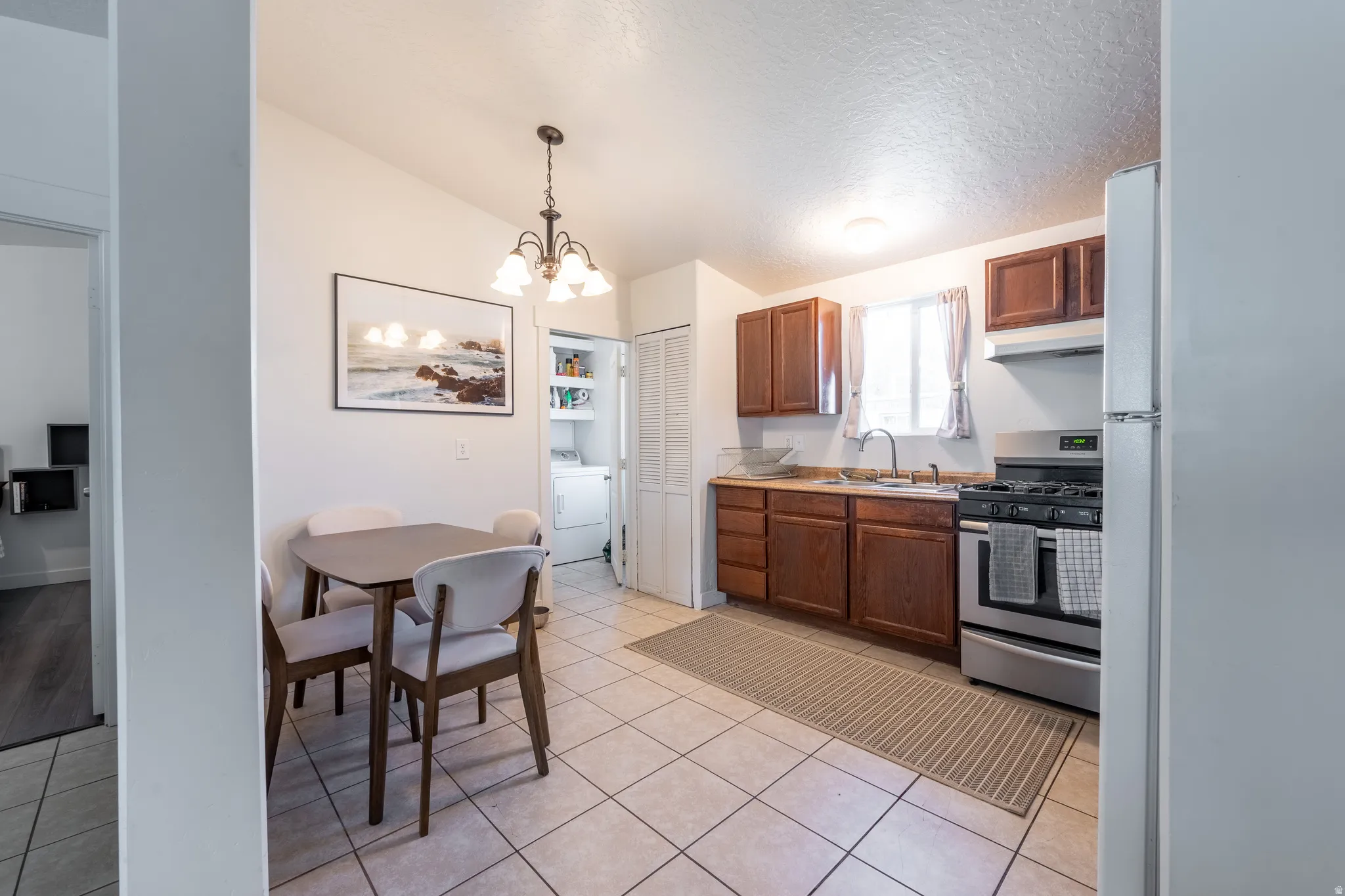 Kitchen featuring gas stove, a chandelier, light countertops, light tile patterned floors, and freestanding refrigerator