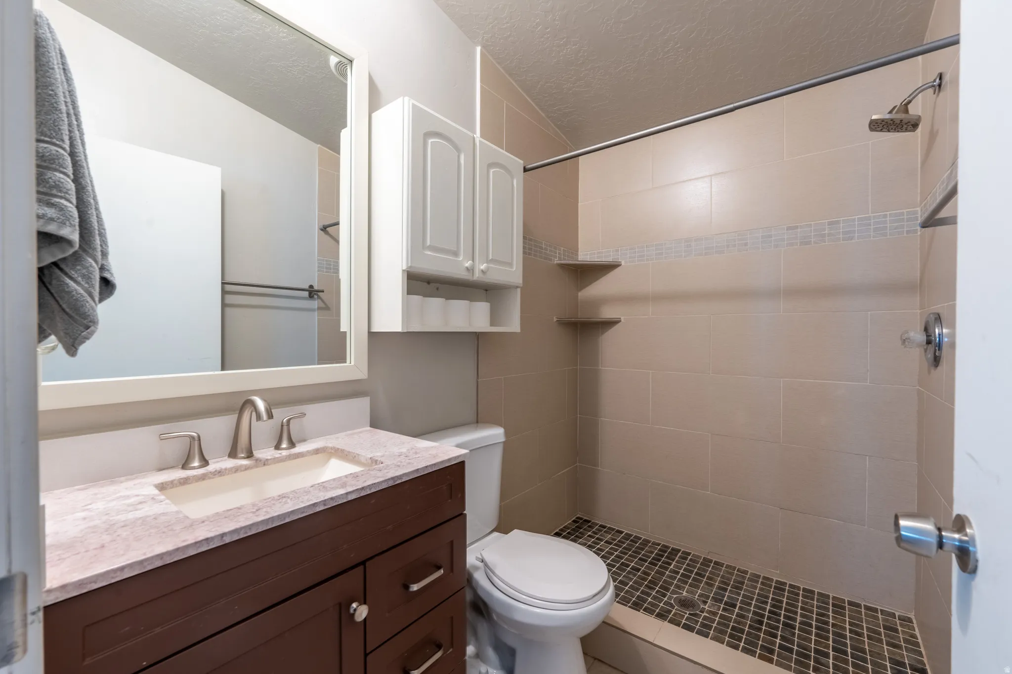 Bathroom with vanity, a textured ceiling, and a shower stall