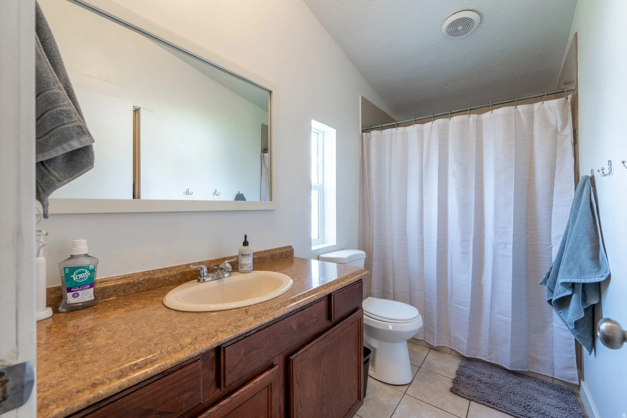 Bathroom with vanity, a shower with curtain, and light tile patterned flooring