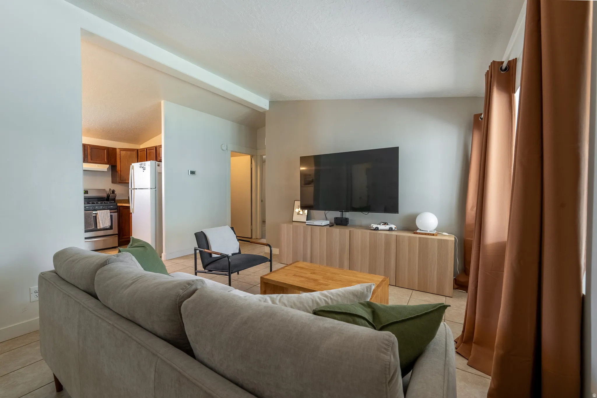 Living area featuring lofted ceiling with beams and light tile patterned flooring