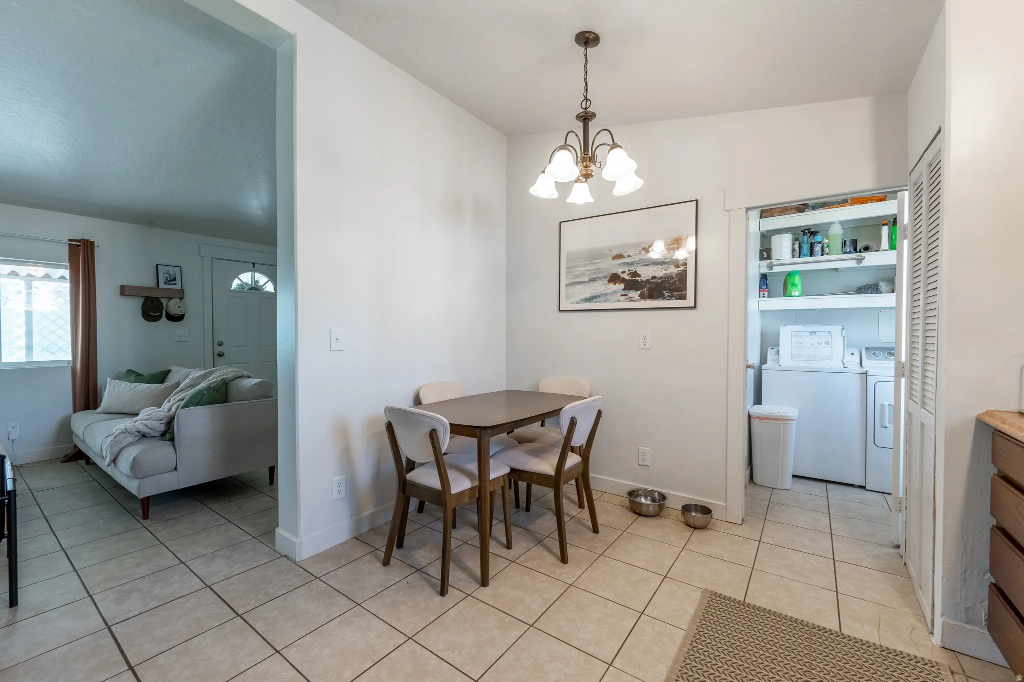 Dining space with suspended lighting, washer and dryer, and light tile patterned floors