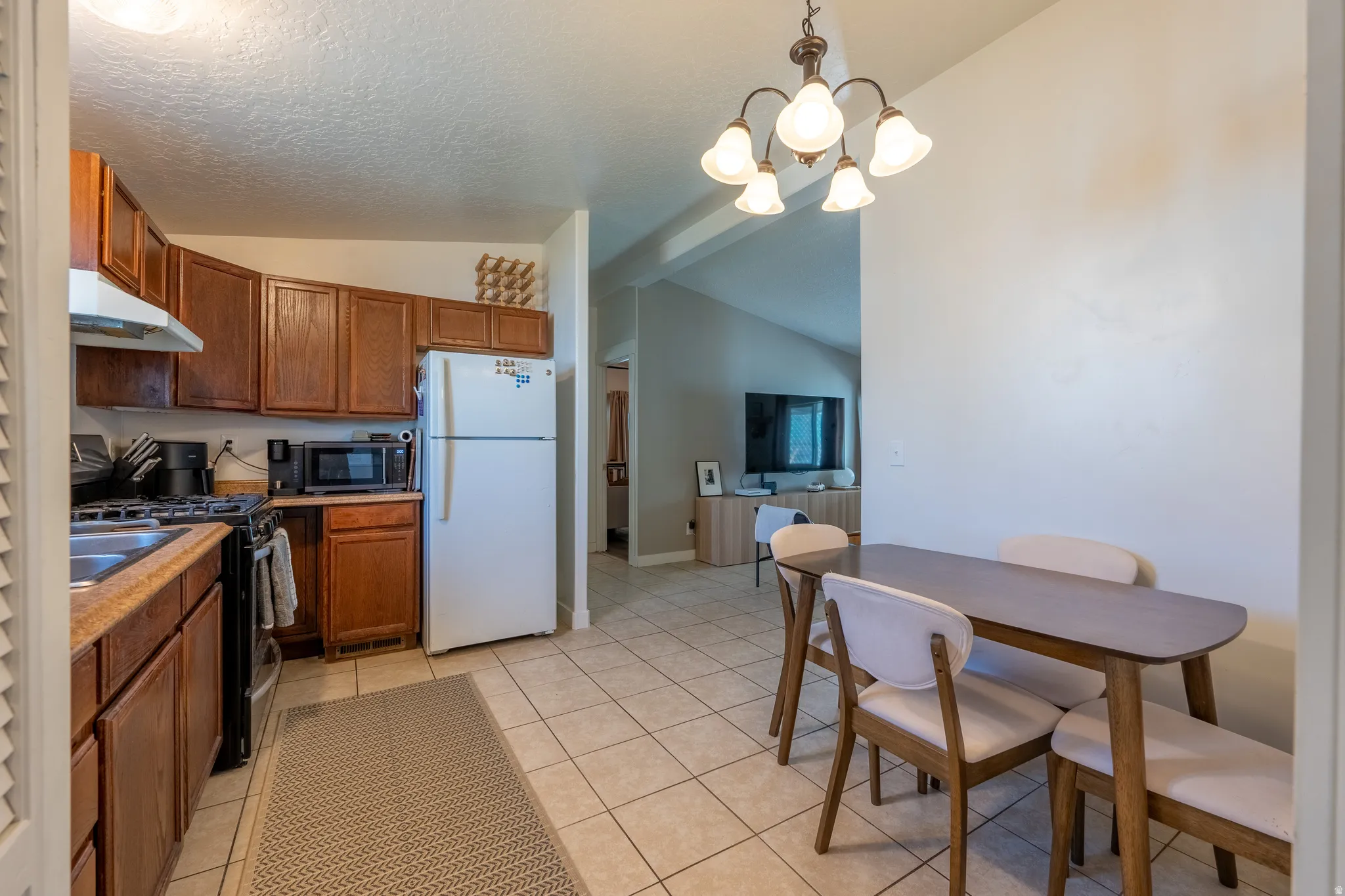 Kitchen with range with gas cooktop, freestanding refrigerator, wood finish cabinets, suspended lighting, and light countertops