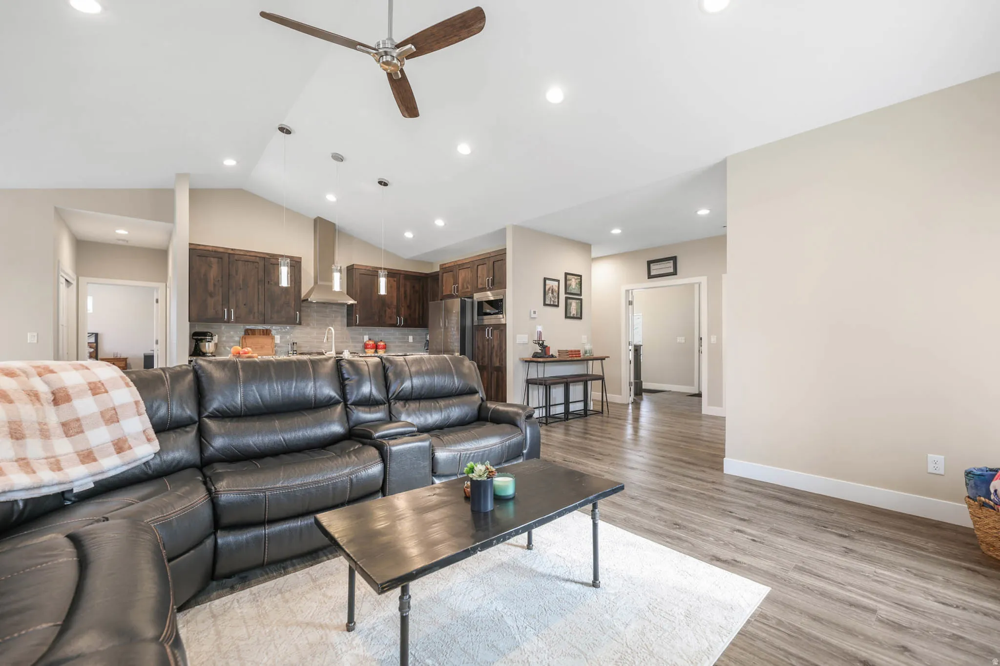 Living room featuring a ceiling fan, light wood-style flooring, recessed lighting, and vaulted ceiling
