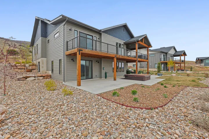 Back of property with a patio area, a deck, and a hot tub