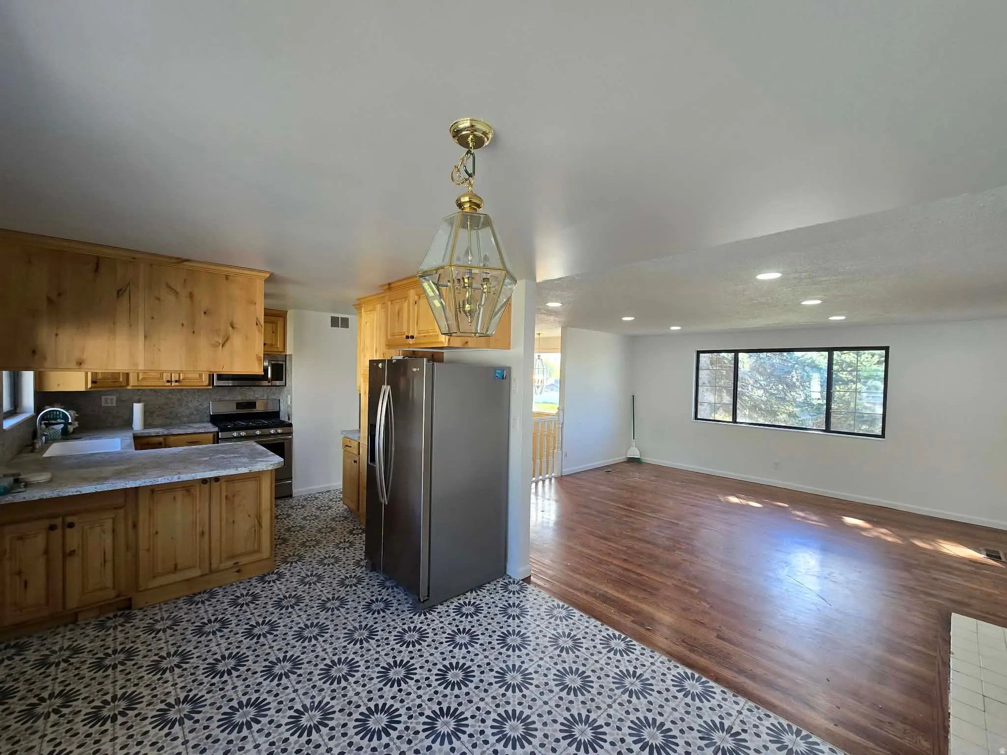 Kitchen featuring stainless steel appliances, open floor plan, a peninsula, light stone countertops, and a chandelier