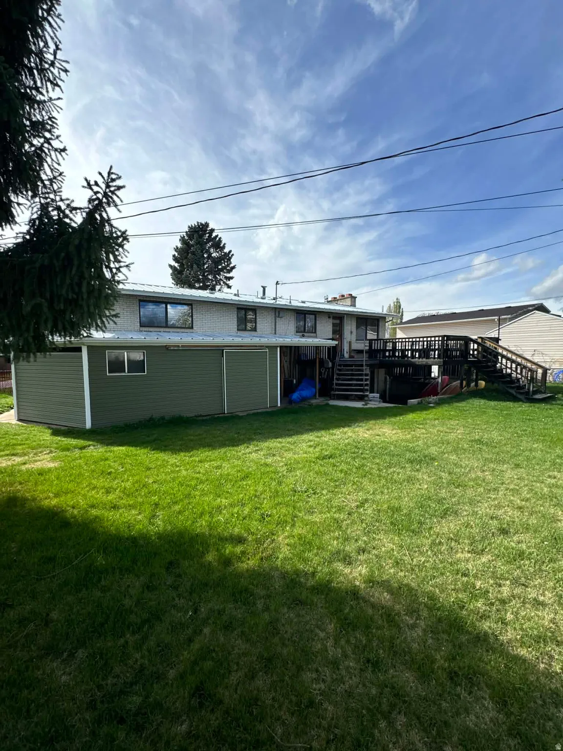 Rear view of property featuring a deck and a lawn