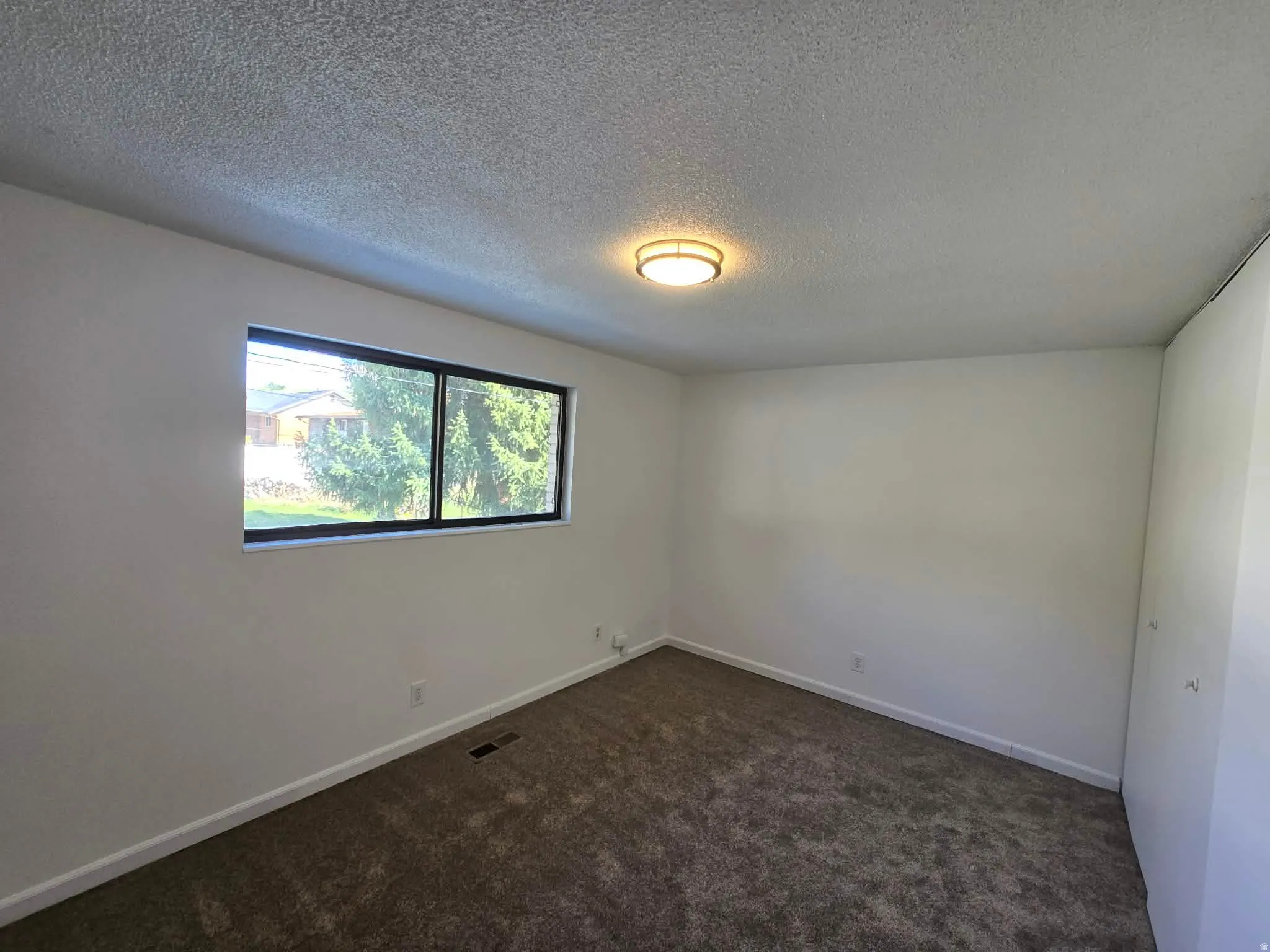 Spare room with dark carpet and a textured ceiling